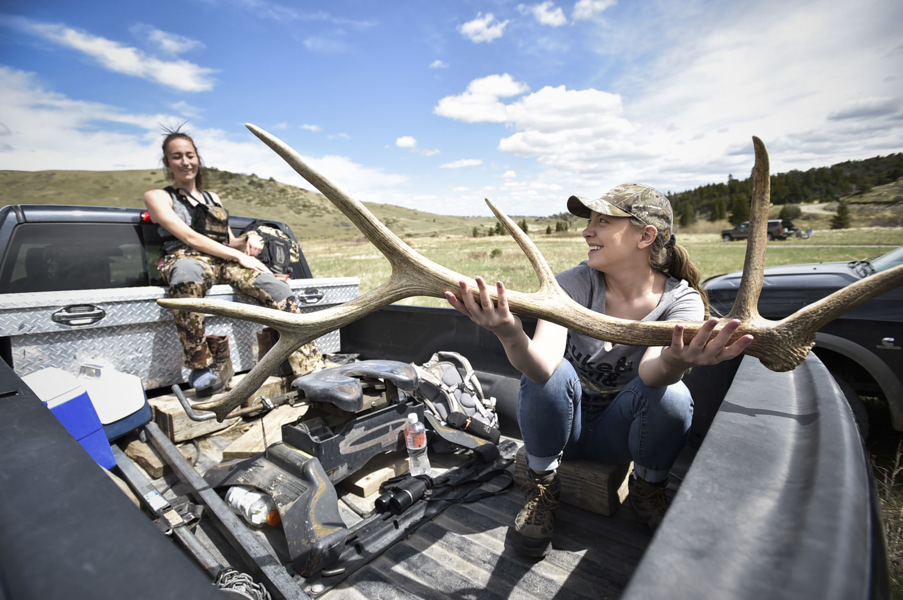 Mariah Hayes, right, and Bailee Pottratz joke in the bed of a pickup